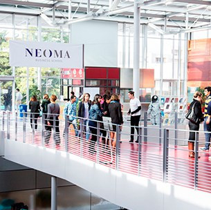 Étudiants marchant sur la passerelle intérieure du campus NEOMA à Reims